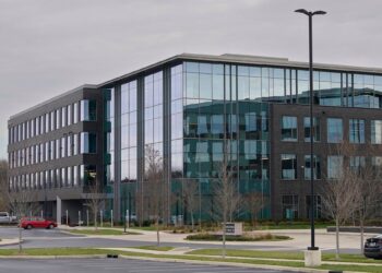 A photo shows a gray and blue building in the center.