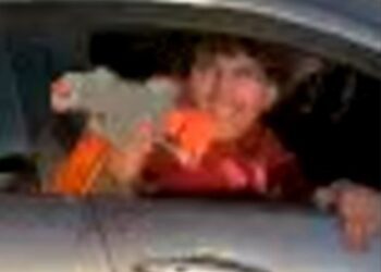 screenshot of surveillance footage shows the unidentified perp wearing an orange jacket shooting a pellet gun out the silver sedan's window on May 2, 2025, hitting a 42-year-old woman in the back while she was carrying a baby
