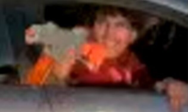 screenshot of surveillance footage shows the unidentified perp wearing an orange jacket shooting a pellet gun out the silver sedan's window on May 2, 2025, hitting a 42-year-old woman in the back while she was carrying a baby