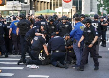 NYPD officers detaining a demonstrator at an ICE protest.