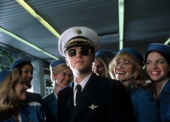 Leonardo DiCaprio in a pilot uniform surrounded by flight attendants in *Catch Me If You Can*.