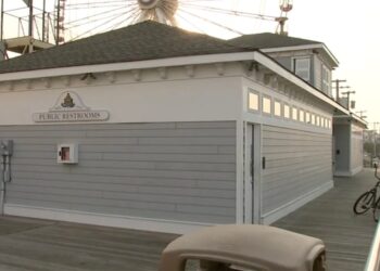Public restrooms on a boardwalk with a Ferris wheel in the background.