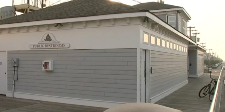 Public restrooms on a boardwalk with a Ferris wheel in the background.
