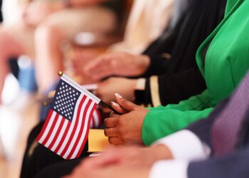 Person holding an American flag at a naturalization ceremony.