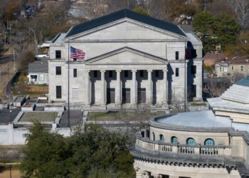 An aerial photograph of the Mississippi Supreme Court building, a beige, multi-story building with a pointed roof and columns.