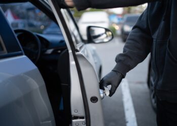 Close-up of a thief attempting to break into a car.