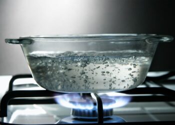 Glass saucepan of boiling water on a gas stove.