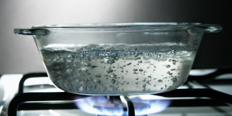 Glass saucepan of boiling water on a gas stove.