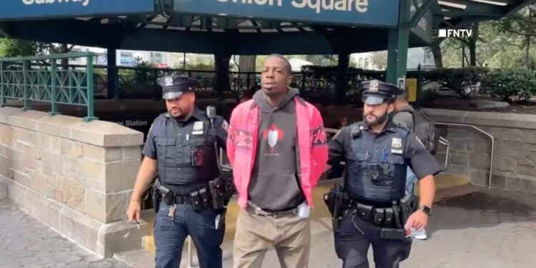 Aaron Walker escorted out of the Union Square subway station by two police officers.