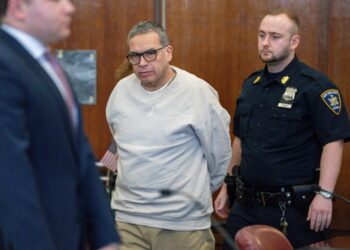 espinoza in grey sweatshirt and khakis with his arms behind him during a court appearance