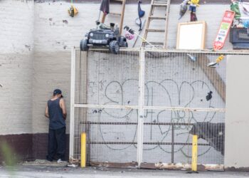 A man pees outside a Rite Aid in Astoria.