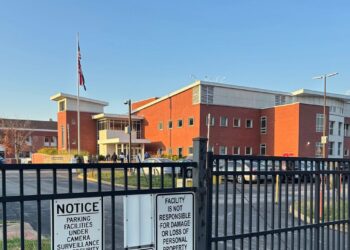 A photo of a brick building behind a black fence.