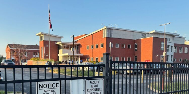 A photo of a brick building behind a black fence.