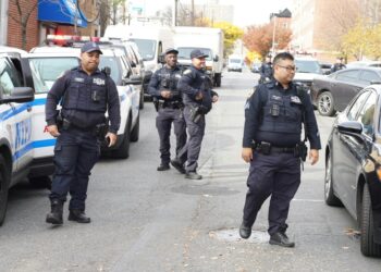 Police officers on a street following an incident where a teenager was shot.