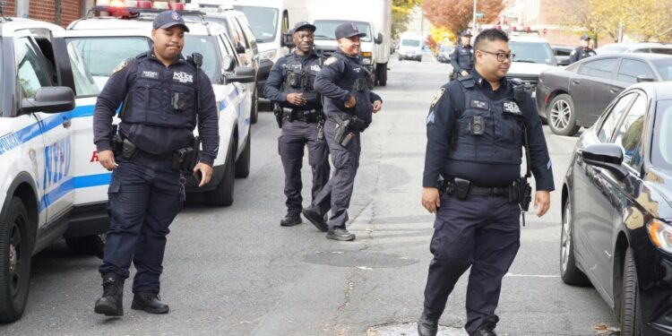 Police officers on a street following an incident where a teenager was shot.