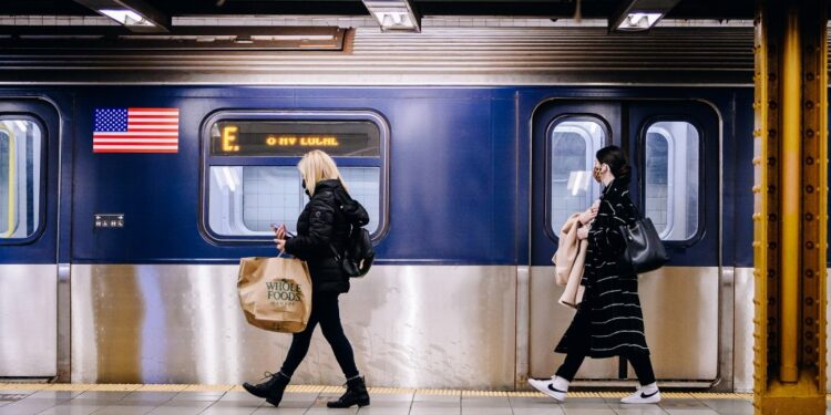 People wearing protective masks walk past a subway train.
