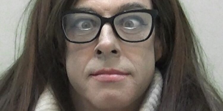 Natalie Wolf, a convicted child sex offender, wearing glasses, a wig, and a cream-colored turtleneck.
